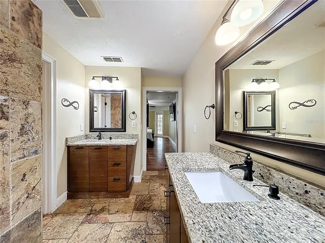 a bathroom with a granite countertop double vanity sink and a mirror