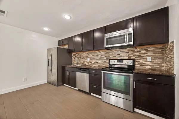 a kitchen with stainless steel appliances kitchen island granite countertop a stove and a microwave