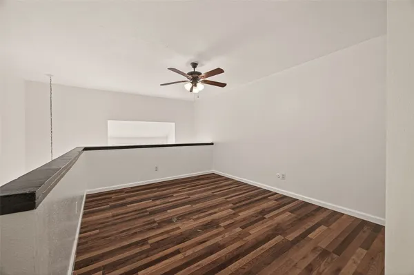 a view of a room with wooden floor and a ceiling fan