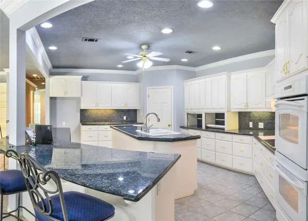 a large kitchen with granite countertop a sink a counter top space appliances and cabinets