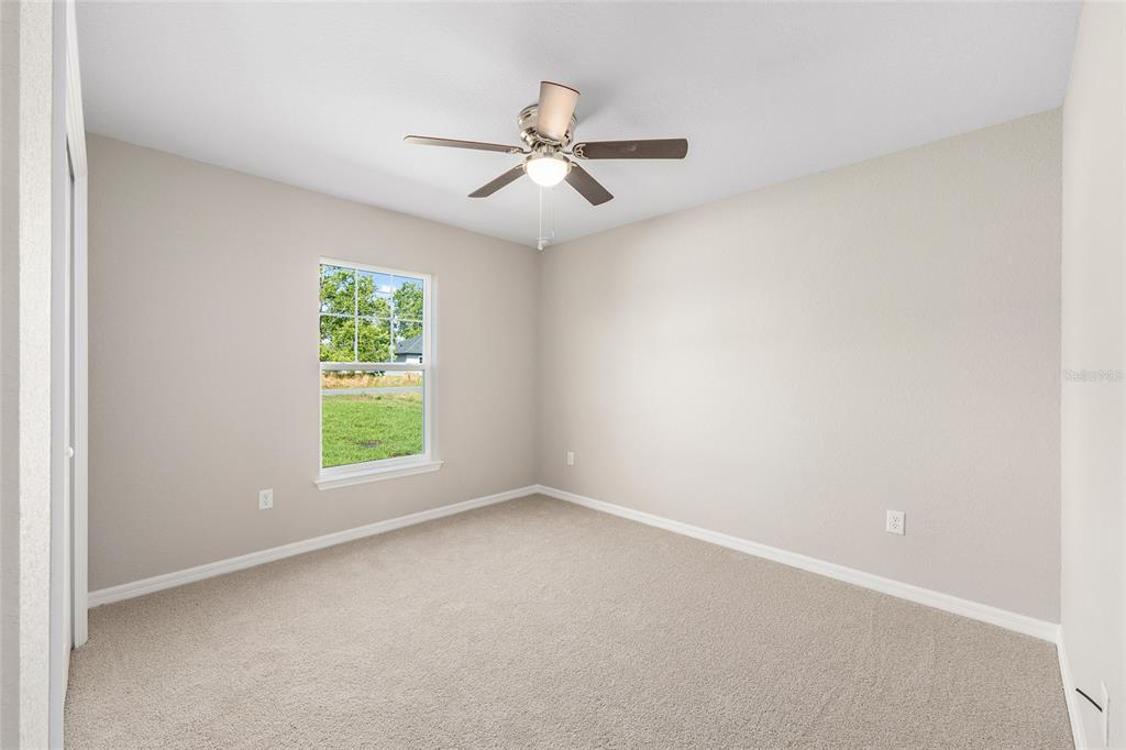 17574 Southwest 112th Place Dunnellon, FL 34432 - Photo 18 of 26 an empty room with windows and ceiling fan