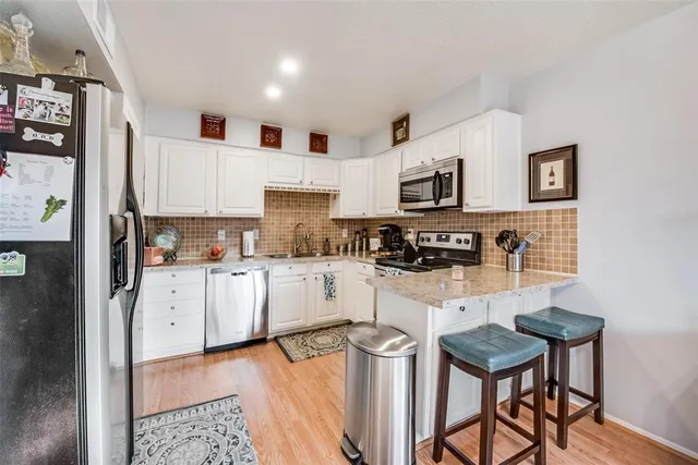 a kitchen with stainless steel appliances granite countertop a refrigerator and a stove top oven