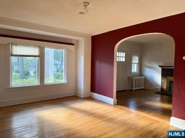 a view of an empty room with window and wooden floor