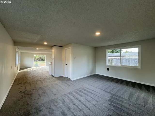 a view of empty room with kitchen and window