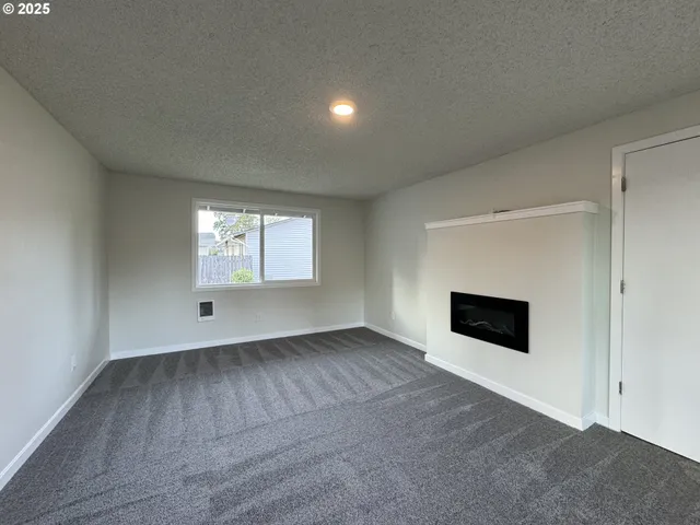 a view of an empty room with a fireplace and a window