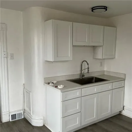 a kitchen with white cabinets and sink