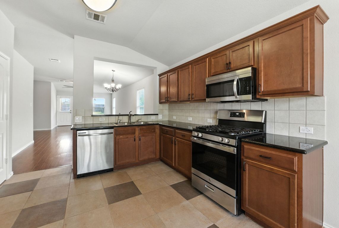 2840 Hearthsong Loop Round Rock, TX 78665 - Photo 13 of 39 a kitchen with stainless steel appliances granite countertop a stove a sink dishwasher and a microwave oven on the blue kitchen countertops