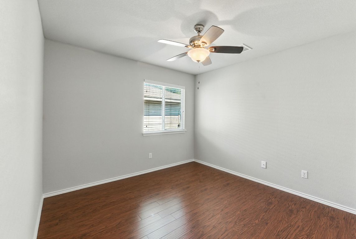 2840 Hearthsong Loop Round Rock, TX 78665 - Photo 19 of 39 an empty room with wooden floor chandelier fan and windows