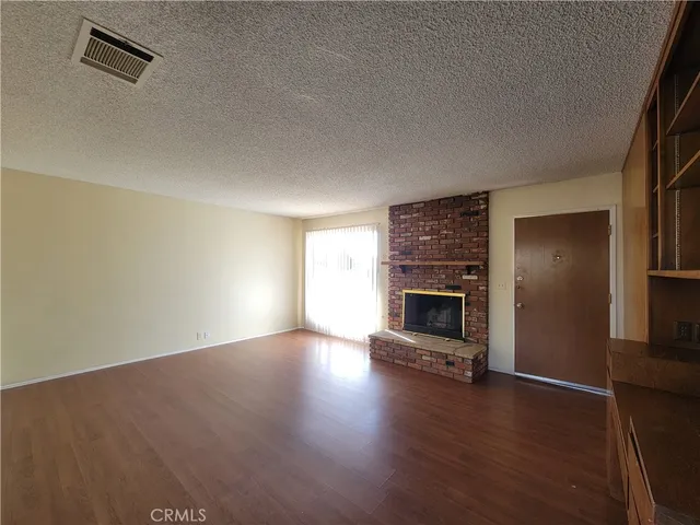 an empty room with wooden floor fireplace and windows