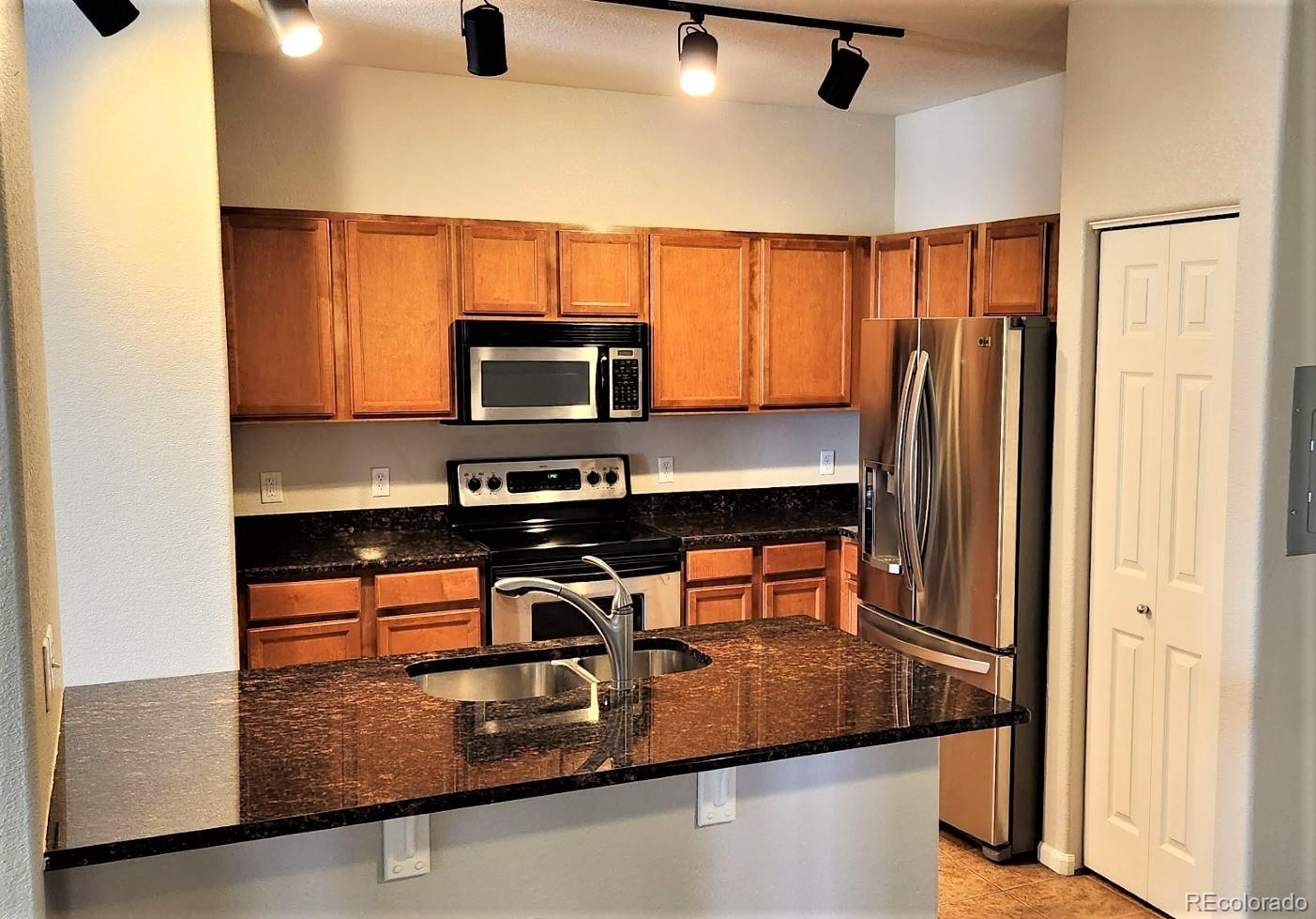 10787 Twenty Mile Road, Unit 305 Parker, CO 80134 - Photo 16 of 28 a kitchen with stainless steel appliances granite countertop a refrigerator and a stove top oven