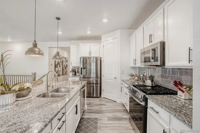 a kitchen with stainless steel appliances granite countertop a sink stove and refrigerator