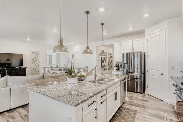 a kitchen with stainless steel appliances kitchen island granite countertop a sink a counter and chairs