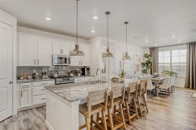 a kitchen with stainless steel appliances kitchen island granite countertop a stove a sink a dining table and chairs with wooden floor