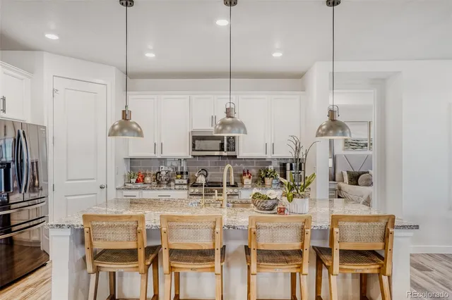 a kitchen with kitchen island granite countertop a dining table chairs stainless steel appliances and cabinets
