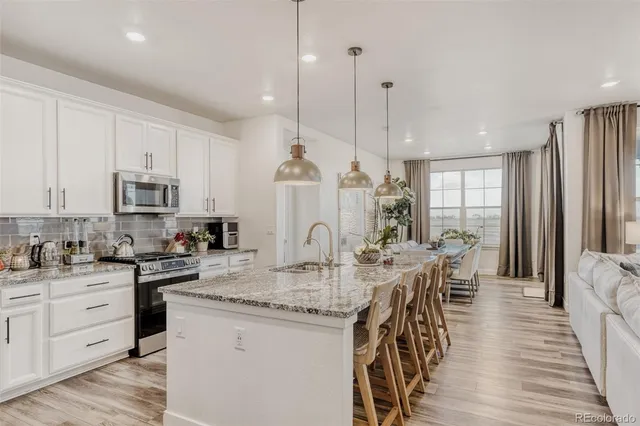 a view of a kitchen with kitchen island granite countertop a table chairs sink and cabinets