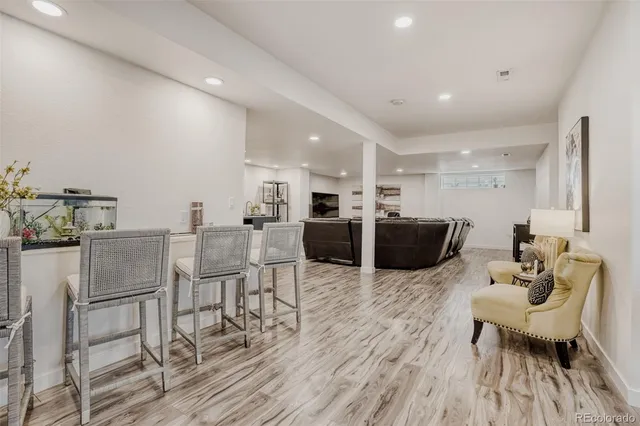 a living room with furniture a wooden floor and kitchen view