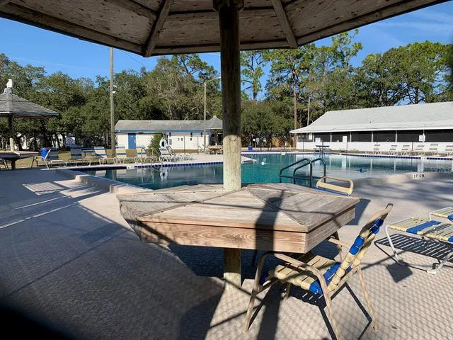 a view of swimming pool with lawn chairs under an umbrella