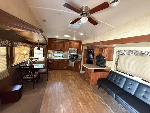a living room with couches a stove and kitchen view with wooden floor