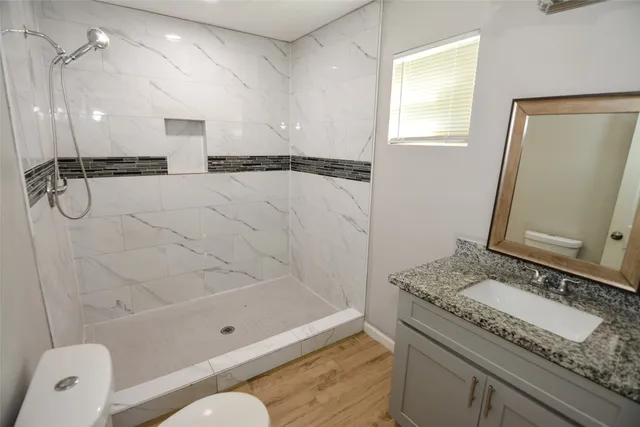a bathroom with a granite countertop sink a toilet and shower