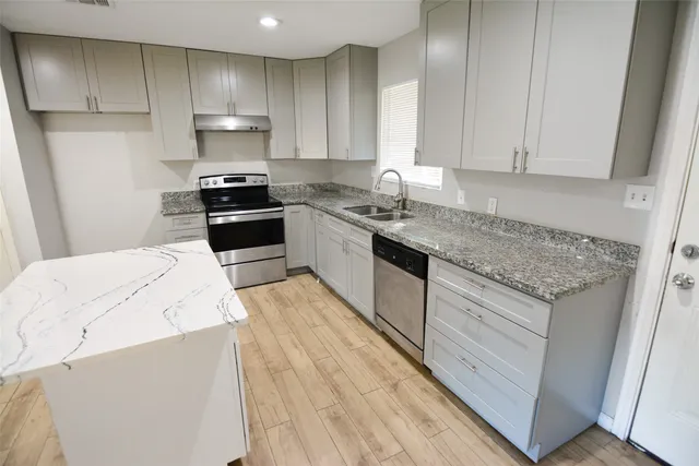 a kitchen with granite countertop wooden cabinets and white appliances