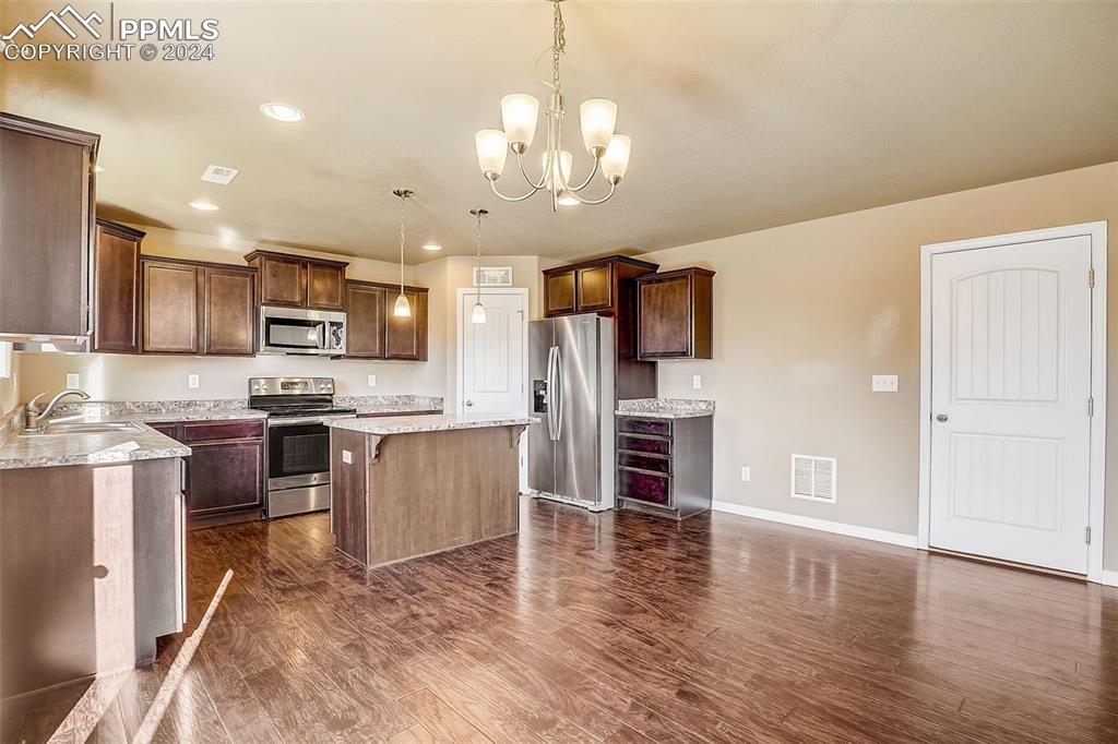11642 Avena Road Peyton, CO 80831 - Photo 12 of 50 a kitchen with stainless steel appliances granite countertop a refrigerator oven a sink dishwasher and white cabinets with wooden floor