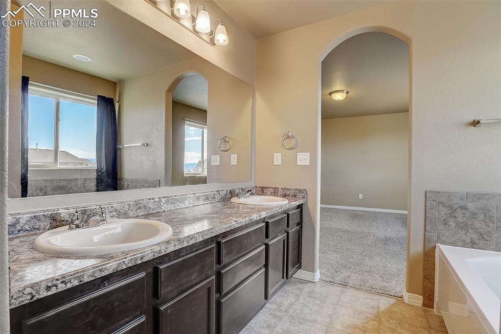 11642 Avena Road Peyton, CO 80831 - Photo 29 of 50 a bathroom with a granite countertop sink a double vanity and a mirror