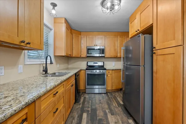a kitchen with granite countertop a refrigerator stove and sink