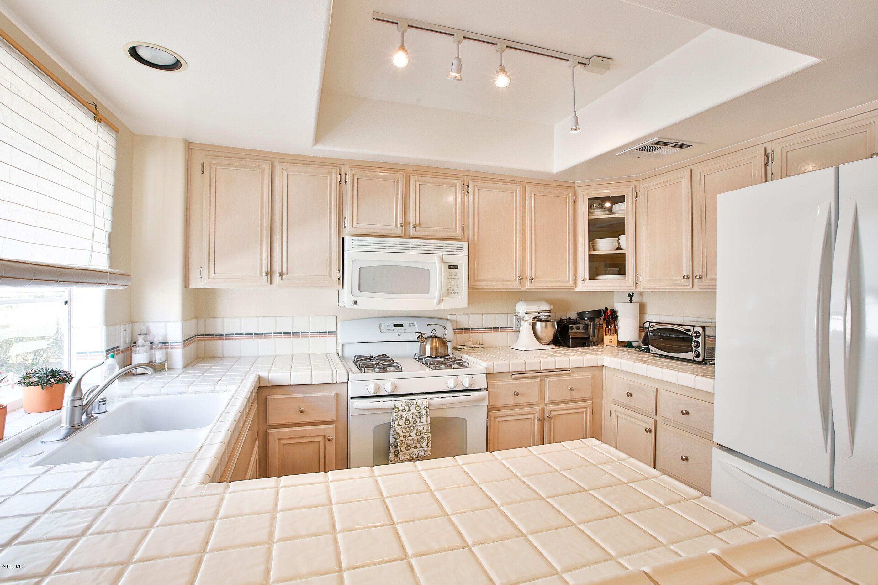 5340 Las Virgenes Road, Unit 11 Calabasas, CA 91302 - Photo 9 of 19 a kitchen with white cabinets a sink appliances and a window