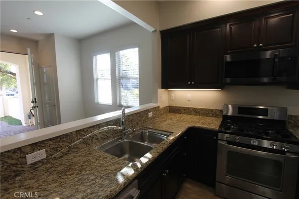 a kitchen with granite countertop stainless steel appliances a stove a sink and a microwave