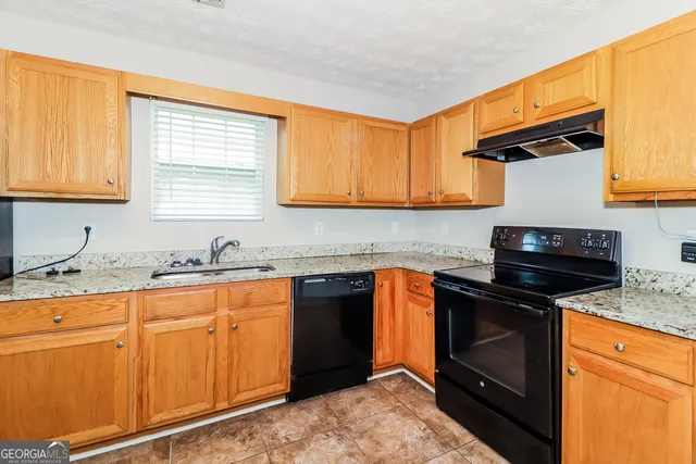 a kitchen with granite countertop a sink stove and refrigerator