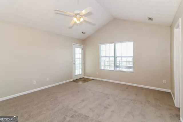an empty room with a chandelier fan and entryway