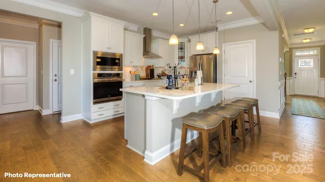 a kitchen with stainless steel appliances granite countertop a stove top oven a sink a refrigerator and a dining table with wooden floor