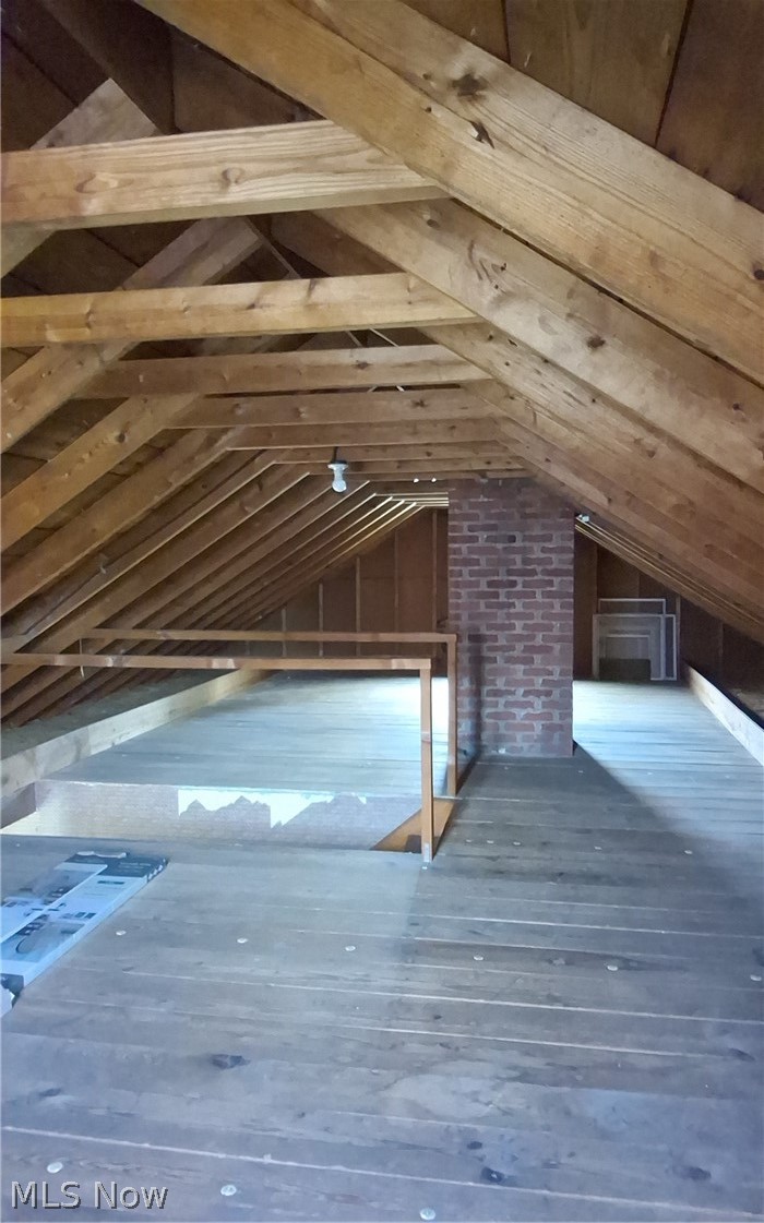 236 Bowland Road Mansfield, OH 44907 - Photo 28 of 34 Exposed wooden rafter ceiling with plank flooring, a partial brick chimney, and a wooden railing providing a distinct division of space