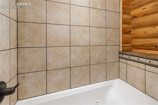 111 Blue Spruce Road Divide, CO 80814 - Photo 29 of 46 Full bathroom featuring a jetted tub and rustic walls