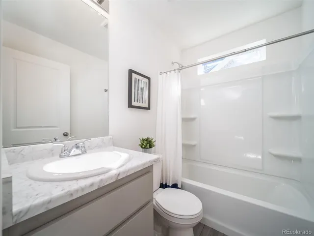 a bathroom with a granite countertop sink a toilet and shower