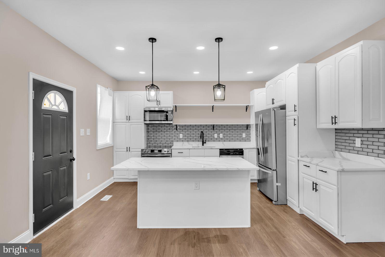 a large kitchen with stainless steel appliances kitchen island a large counter top and a refrigerator