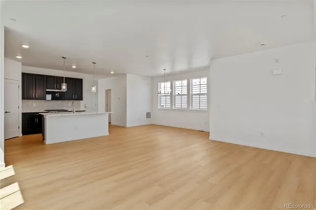 a view of an empty room with kitchen and a window