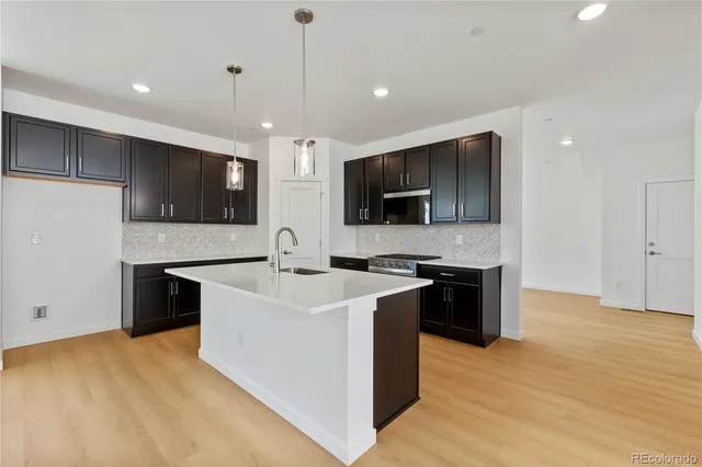 a large kitchen with stainless steel appliances a large counter top a stove a sink a refrigerator and a microwave