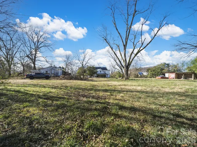 a backyard of a house with large trees and wooden fence