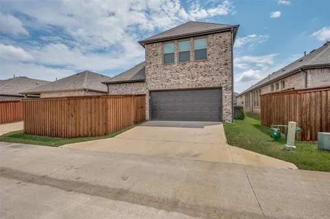 a front view of a house with yard plants and wooden fence