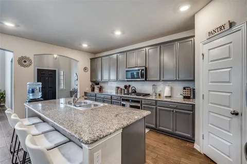 a kitchen with kitchen island granite countertop a sink cabinets and stainless steel appliances