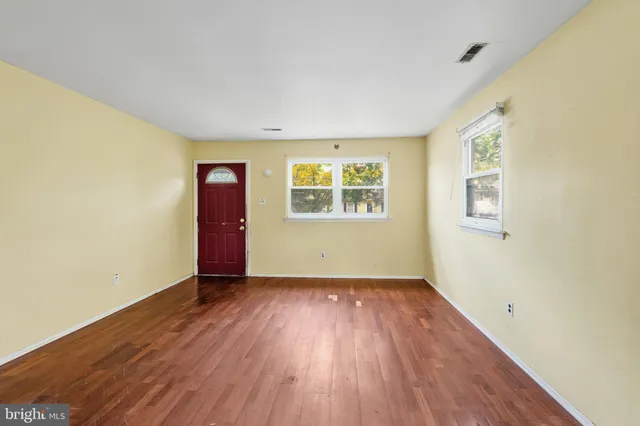 an empty room with wooden floor and windows