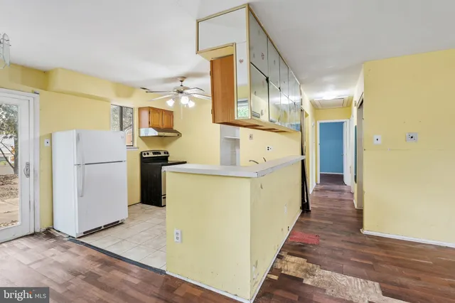 a view of a hallway with wooden floor and a kitchen