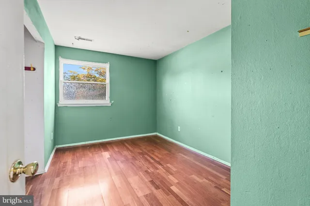 a view of an empty room with window and wooden floor