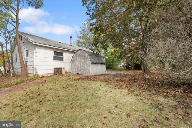 a backyard of a house with large trees and wooden fence
