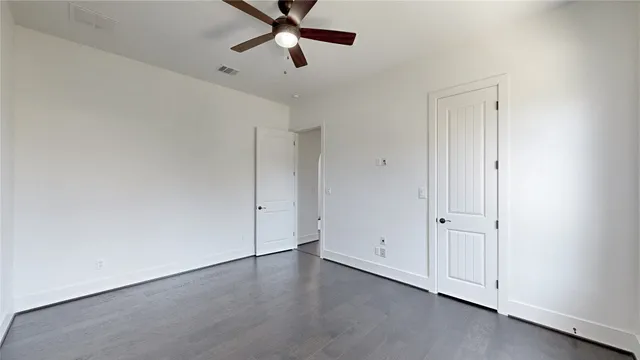 an empty room with wooden floor ceiling fan and windows