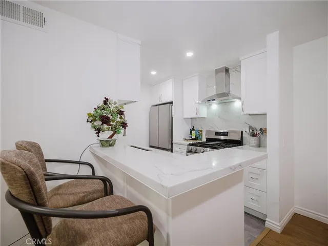 a kitchen with stainless steel appliances kitchen island granite countertop a sink a stove and a refrigerator