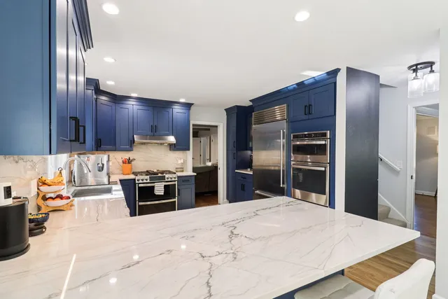 a kitchen with granite countertop a refrigerator and a stove top oven