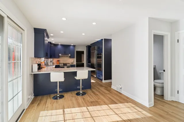 a room with stainless steel appliances kitchen island granite countertop a refrigerator and a sink