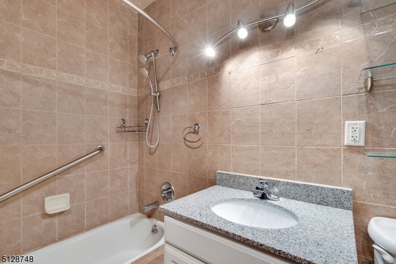 7 Prospect Street, Unit 303 Morristown, NJ 07960 - Photo 21 of 22 a bathroom with a granite countertop sink a toilet and shower